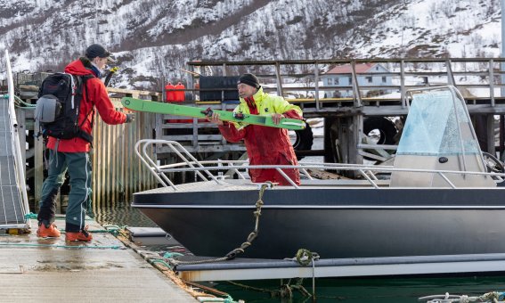 boot, zwei personen beim entladen der ski