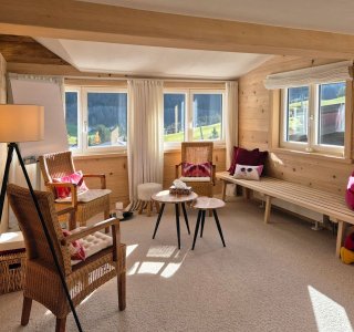 Heller Raum mit Holzinterieur, bequemen Stühlen und Blick auf die Berglandschaft. Ideal zum Entspannen oder Arbeiten.