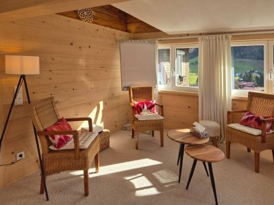 Der Raum ist hell und einladend, mit bequemen Stühlen und tollem Ausblick auf die Berge und die Natur.