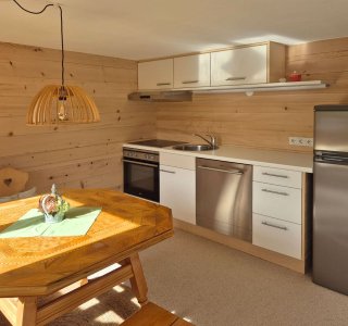 Die helle Küche hat Holzverkleidungen, moderne Geräte und einen einladenden Esstisch. Ideal für einen entspannten Aufenthalt.