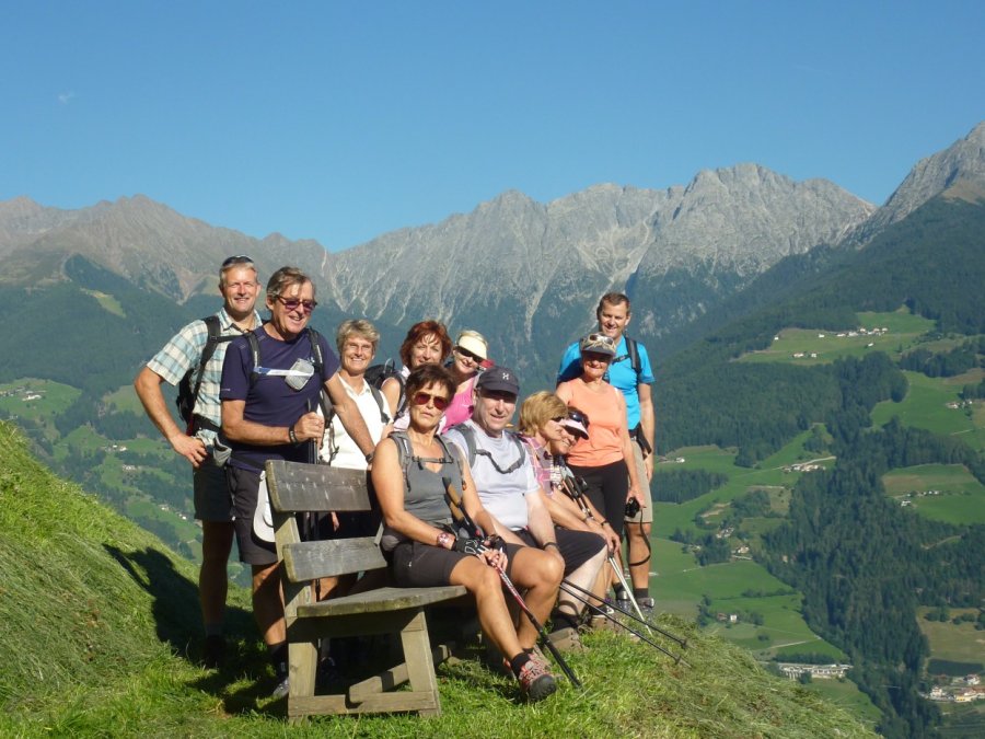 Eine Wandergruppe hat auf dem Meraner Höhenweg eine Sitzbank zum Ausruhen erreicht.