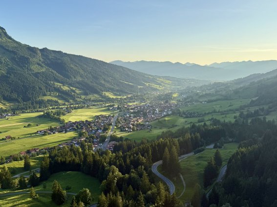 Blick auf das Tal und die Berge am Abend Ein Blick auf das Tal und die Berge während des Abends. Die Sonne scheint über die Landschaft und die Häuser.