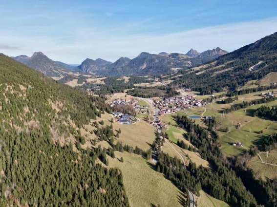 Berglandschaft mit einem Dorf in den Alpen Das Bild zeigt eine weite Berglandschaft mit einem kleinen Dorf in den Alpen. Es ist tagsüber mit klarem Himmel.
