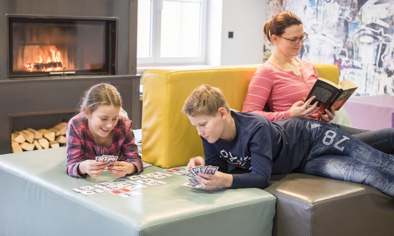 Gemütliches Karten spielen am Kamin im Wohnzimmer des Oberstdorf Hostels.