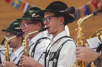 Musikkapelle Oberstdorf Die Blasmusikgruppe spielt mit Saxophonen während eines Festes. Menschen feiern und genießen die Musik.