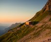 Ein Blick auf die Hütten in den Bergen während des Sonnenuntergangs. Die Landschaft zeigt Hügel und eine ruhige Atmosphäre.