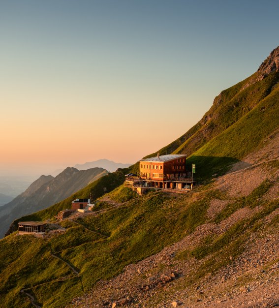 Waltenberger Haus im Sonnenuntergang Ein Blick auf die Hütten in den Bergen während des Sonnenuntergangs. Die Landschaft zeigt Hügel und eine ruhige Atmosphäre.