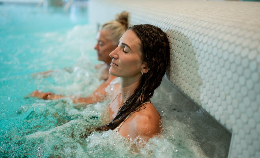 Entspannung im Wasser mit Freunden Zwei Frauen sitzen im Spa in warmem Wasser und genießen den Moment. Der Fokus liegt auf Entspannung und Freundschaft.