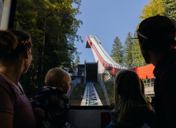Familie schaut auf eine Sprungschanze in der Natur