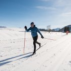 Ein Langläufer gleitet bei sonnigem Winterwetter über eine präparierte Loipe in Bolsterlang.