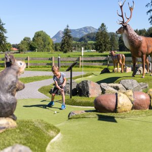 A child plays on the adventure golf course among large animal figures in Fischen.