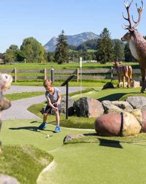 Ein Kind spielt auf der Erlebnis-Golf-Anlage zwischen großen Tierfiguren in Fischen.