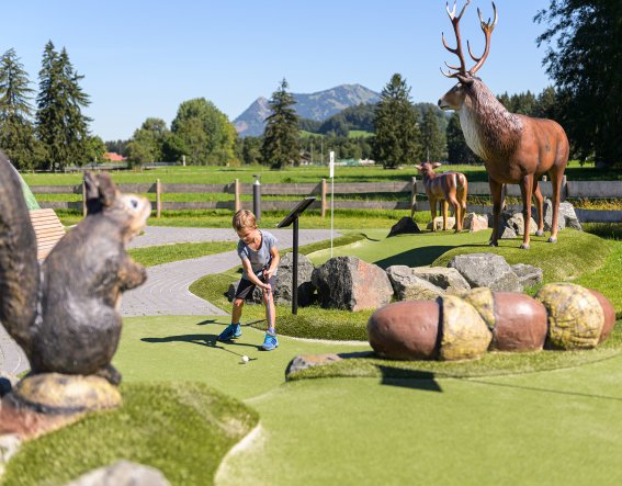 Un enfant joue au golf aventure parmi de grandes figures animales à Fischen À Fischen, un enfant joue sur le parcours de mini-golf au milieu de grandes figurines d'animaux.