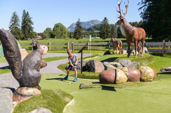 Un enfant joue au golf aventure parmi de grandes figures animales à Fischen À Fischen, un enfant joue sur le parcours de mini-golf au milieu de grandes figurines d'animaux.