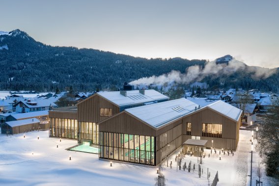 Exterior view of the Oberstdorf thermal baths in winter, nestled in the Allgäu mountains, overlooking the pools Nestled amidst the snow, the Oberstdorf thermal baths in the Allgäu region offer the perfect environment to relax and warm up on a cold winter day.