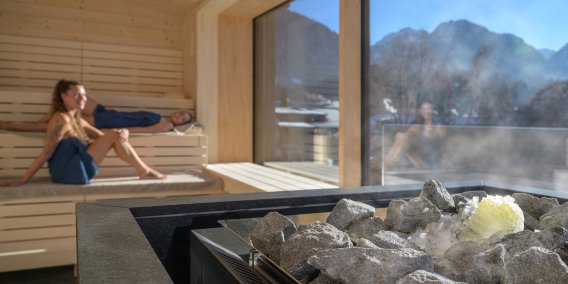 Zwei Frauen entspannen in der Panoramasauna der Therme Oberstdorf mit Blick auf die Allgäuer Berge Entspannender Saunaaufguss in der Panoramasauna mit Blick auf die Oberstdorfer Berge