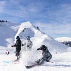 Die Skifahrerin legt sich sportlich in die Kurve und wirbelt vor ihren Freunden eine große Schneefontäne auf.