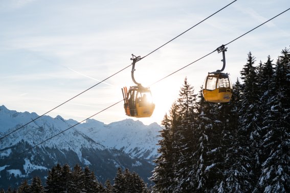 Gondel der Hörnerbahn über der verschneiten Berglandschaft. Die Gondeln der Hörnerbahn schweben über verschneite Wälder und Berge. Die Auffahrt bringt Wintersportler komfortabel in das Gebiet bei Bolsterlang.