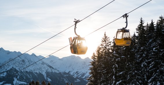 Die Gondeln der Hörnerbahn schweben über verschneite Wälder und Berge. Die Auffahrt bringt Wintersportler komfortabel in das Gebiet bei Bolsterlang.