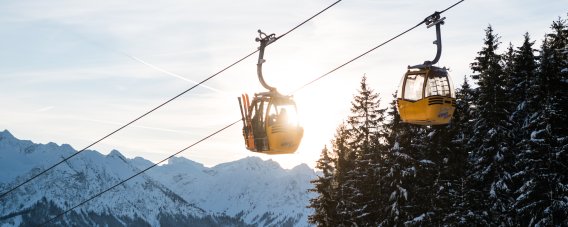 Gondel der Hörnerbahn über der verschneiten Berglandschaft. Die Gondeln der Hörnerbahn schweben über verschneite Wälder und Berge. Die Auffahrt bringt Wintersportler komfortabel in das Gebiet bei Bolsterlang.