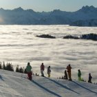 Wanderer über dem winterlichen Nebelmeer bei sonnigem Obheiter. Eine Gruppe ist auf einem sonnigen Höhenweg über dem Nebelmeer unterwegs. Das Allgäuer Wetterphänomen „Obheiter“ sorgt für außergewöhnliche Winterblicke.