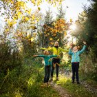 Eine Familie genießt ihre gemeinsame Wanderung durch die herbstliche Natur rund um Ofterschwang. Bewegung, Landschaft und Familienzeit werden miteinander verbunden.