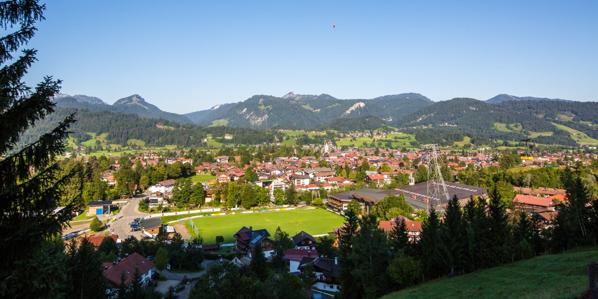 Oberstdorf zu Füßen der Berge Der hübsche Ortskern von Oberstdorf befindet am Fuße der Berge, die Nebelhortalstation findet sich dort, sowie die Skisprungschanzen und eine lebendige Ortsmitte.