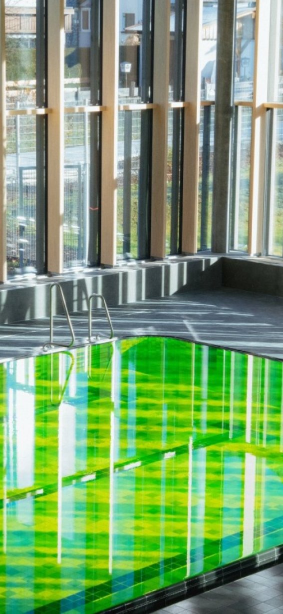 Das Bild zeigt das Sportbecken in der Therme das grün eingefärbt ist.