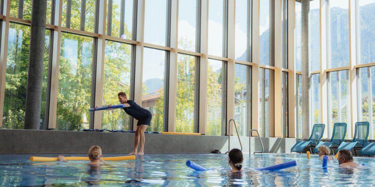 Aqua Gymnastik Einige Personen stehen mit jeweils einer Schwimmnudelim Wasser und machen bei dem kostenlosen Mitmachangebot Aquagymnastik mit. Gemeinsam mit der Trainerin sieht das nach viel Spaß aus.