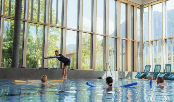 Einige Personen stehen mit jeweils einer Schwimmnudelim Wasser und machen bei dem kostenlosen Mitmachangebot Aquagymnastik mit. Gemeinsam mit der Trainerin sieht das nach viel Spaß aus.