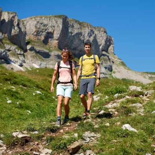Zwischen Mittel- und Bergstation Ein Paar wandert an einem sonnigen Tag auf einem Bergweg. Die Landschaft ist grün und majestätisch.