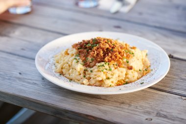 Kässpatzen Auf einem Tisch sind heiße Käsespätzle mit knusprigen Röstzwiebeln angerichtet und bereit zum Essen.