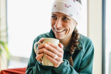 Hände wärmen Eine Frau genießt ihr Getränk in einem gemütlichen Café und lächelt dabei glücklich und entspannt.