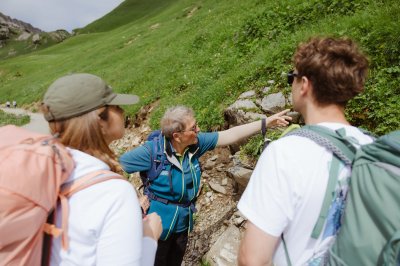 Eine Gruppe von Wanderern hört einem Naturführer aufmerksam zu, während sie in den Bergen sind und die Umgebung erkunden.