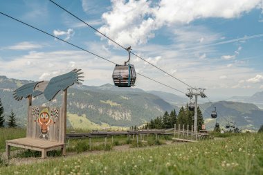 Eine Gondel fährt über die grüne Wiese in den Schweizer Bergen. Die Landschaft ist atemberaubend und zeigt die Natur.