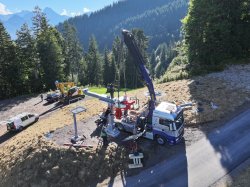 Bau Bergstation Höllwies Okt'25 Ein Kran und verschiedene Fahrzeuge arbeiten an der Bergbahnmitte in den Alpen während eines sonnigen Tages.