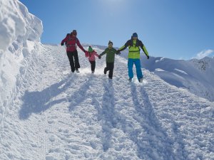 Eine Familie mit zwei Kindern verbringt einen Wintertag im Schnee und genießt das Spielen in der Natur.