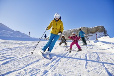 Familie genießt einen sonnigen Skitag beim Skifahren in den Alpen. Kinder lernen und haben Spaß auf der Piste.