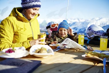 Mutter und Kind genießen das Essen und die Aussicht in den Bergen bei klarem Wetter. Es ist ein sonniger Tag im Winter.