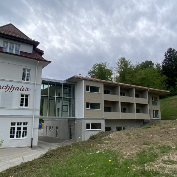 Anbau Privatklinik mit Verbindungssteg zum alten Hotel in den Bergen