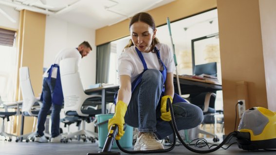 Professioneller-reinigungsdienstmitarbeiter-der-im-buro-einen-staubsauger-verwendet
