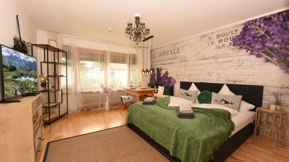 In diesem Raum stehen zwei Betten, ein Fernseher und ein Tisch. Das Zimmer hat eine entspannte Atmosphäre.