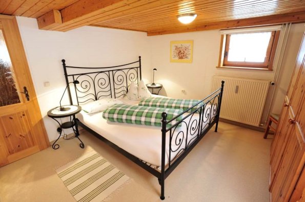 Ein Schlafzimmer mit einem Doppelbett und zwei Nachttischen. Es gibt einen Fensterblick auf die Natur.