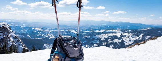 Blue-gray-backpack-with-trekking-gear-side-foreground-mountains-covered