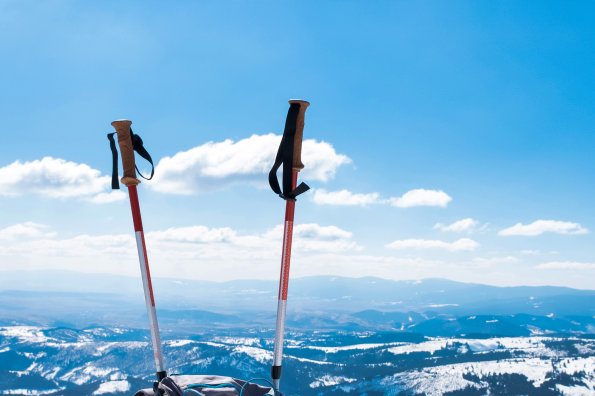 Blue-gray-backpack-with-trekking-gear-side-foreground-mountains-covered b
