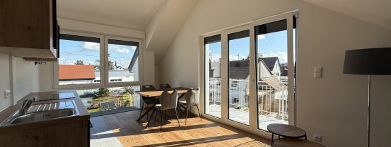 In dieser Wohnung gibt es einen Balkon und viel Licht. Die Küche ist modern und der Essbereich ist einfach gestaltet.