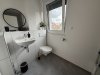 Moderne Toilette mit Fenster und Handwaschbecken
