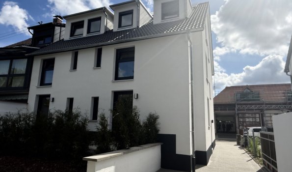 Simon Living Kirchhofstraße 39 Ein modernes Gebäude steht in einer Wohngegend in Deutschland. Der Himmel ist blau mit Wolken.