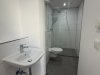 Ein Badezimmer mit einer modernen Dusche, einem Waschbecken und einer Toilette in einer Wohnung.