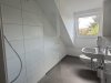 In einem Badezimmer steht eine Dusche mit klaren Wänden und einem Fenster zur Tageslichtversorgung.